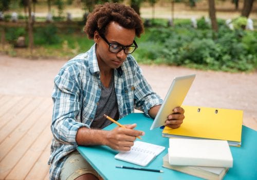 Serious man writing and learning in the park
