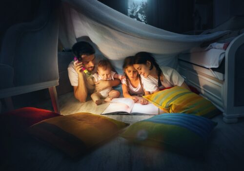 A small girl and grandmother reading book at home.